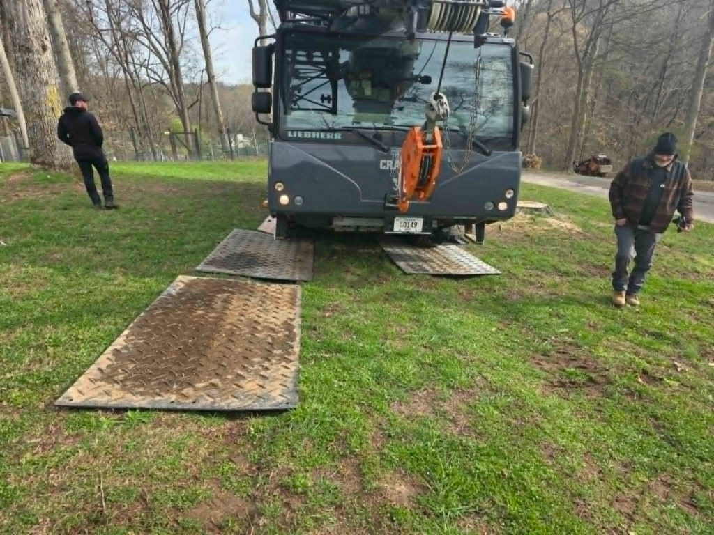 Liebherr crane truck with outriggers on steel ground protection mats placed on residential lawn – White's Tree Service Knoxville TN