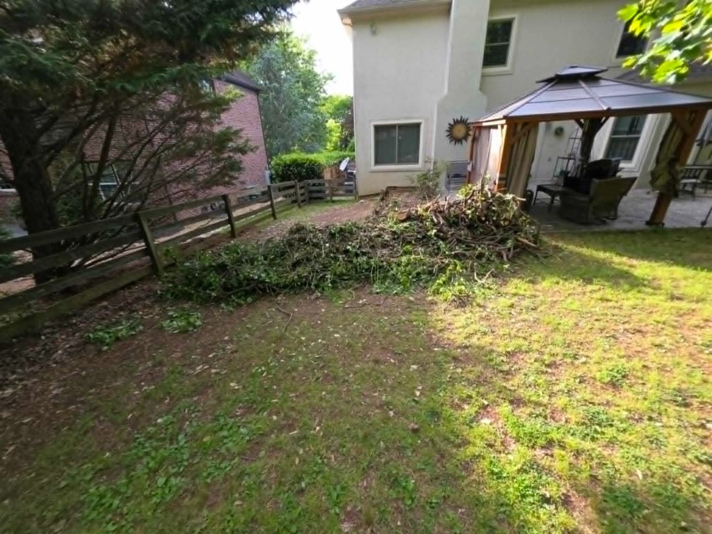 Large brush and branch debris pile staged near backyard gazebo before chipping and removal – White's Tree Service Knoxville TN