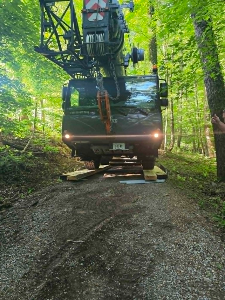 Liebherr crane truck moving carefully down a narrow wooded access path to reach a tree removal site – White's Tree Service Knoxville TN
