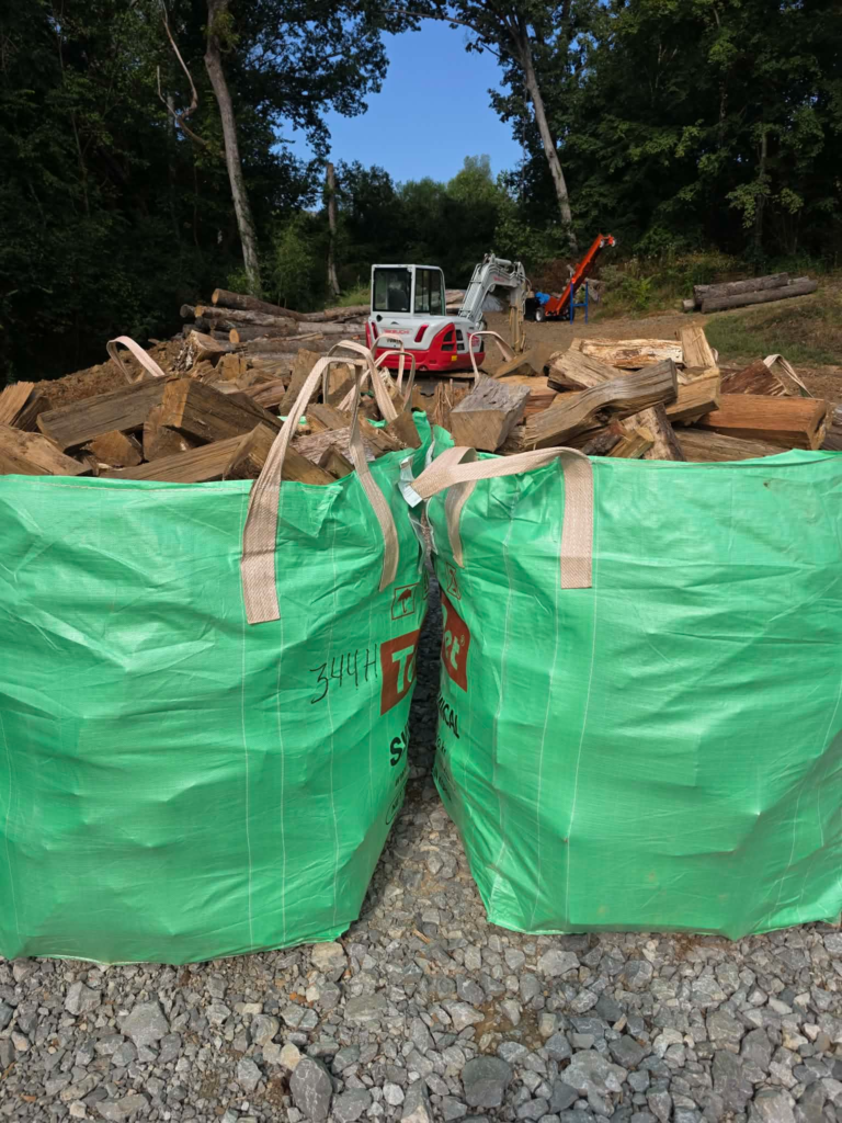 Bulk bags of split firewood with log processing equipment in the background