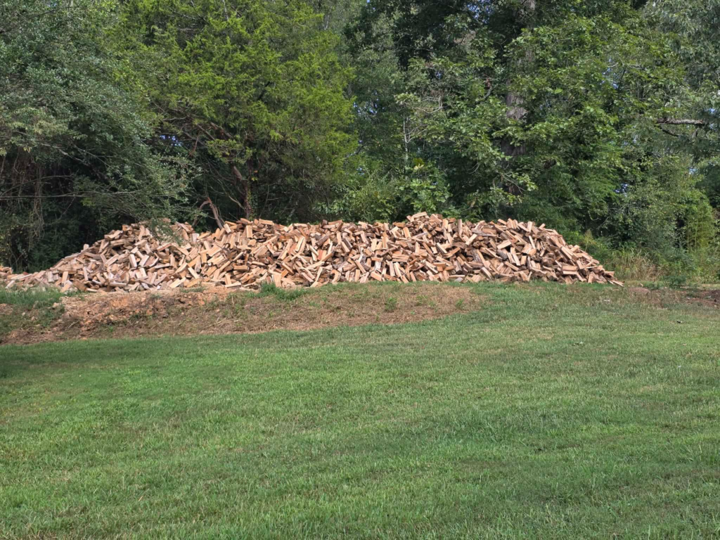 Large pile of freshly split firewood along a tree line in Knoxville, TN