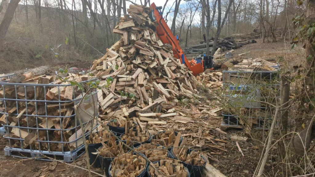 Firewood processor splitting and piling seasoned oak and hardwood firewood at Whites Tree Services in Lenoir City, TN